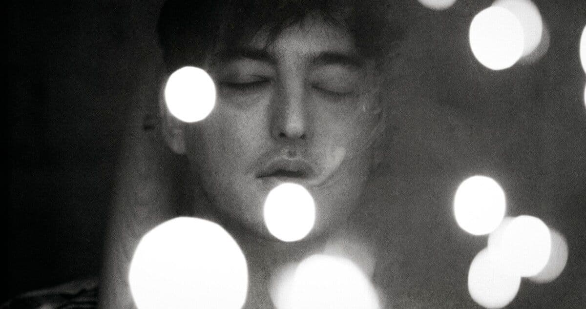 Joji appears in a grainy black-and-white close portrait framed by soft circles of light.