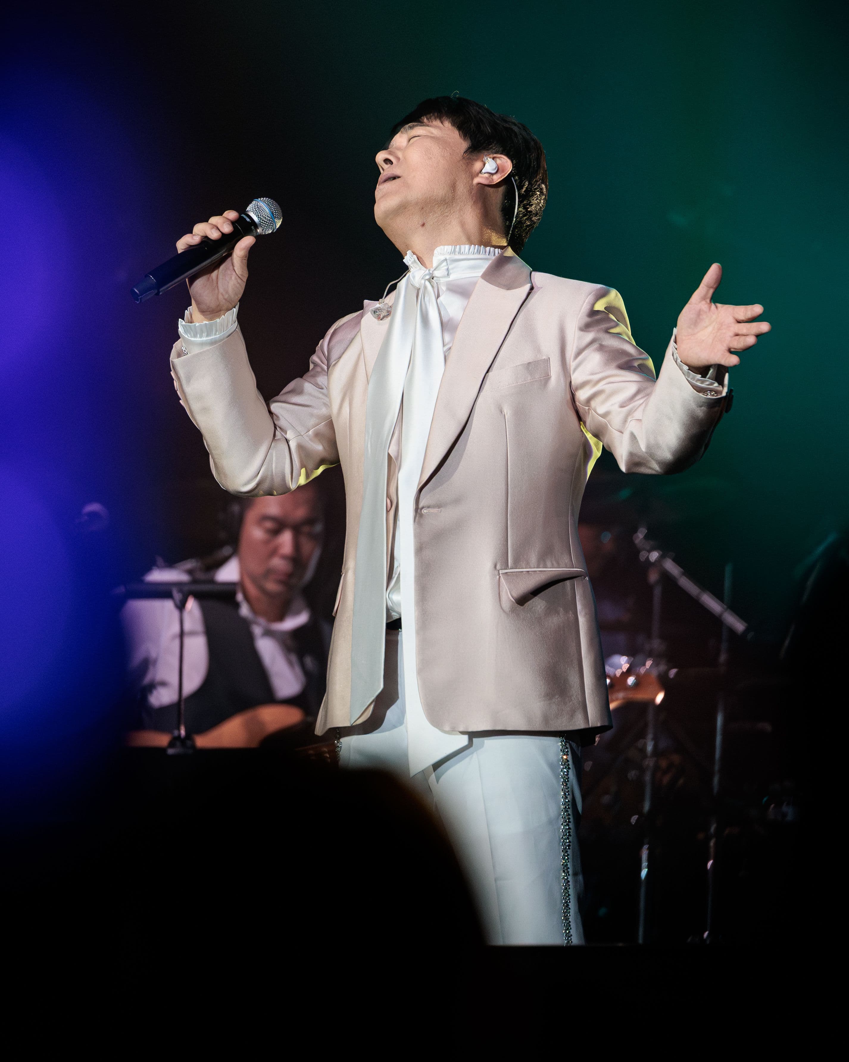 Lim Chang-jung sings with his eyes closed under the stage lights during his Pechanga performance.