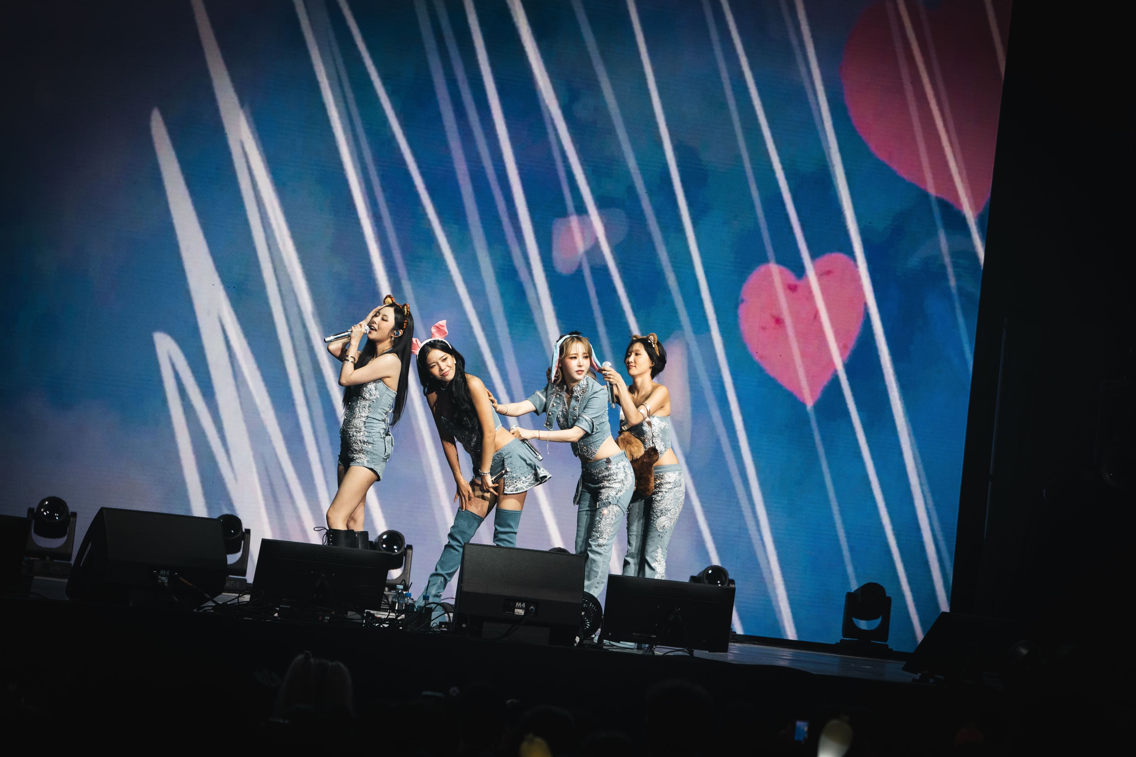 The four members of MAMAMOO perform together in coordinated blue outfits as hearts and white lines fill the massive screen behind them at Crypto.com Arena.