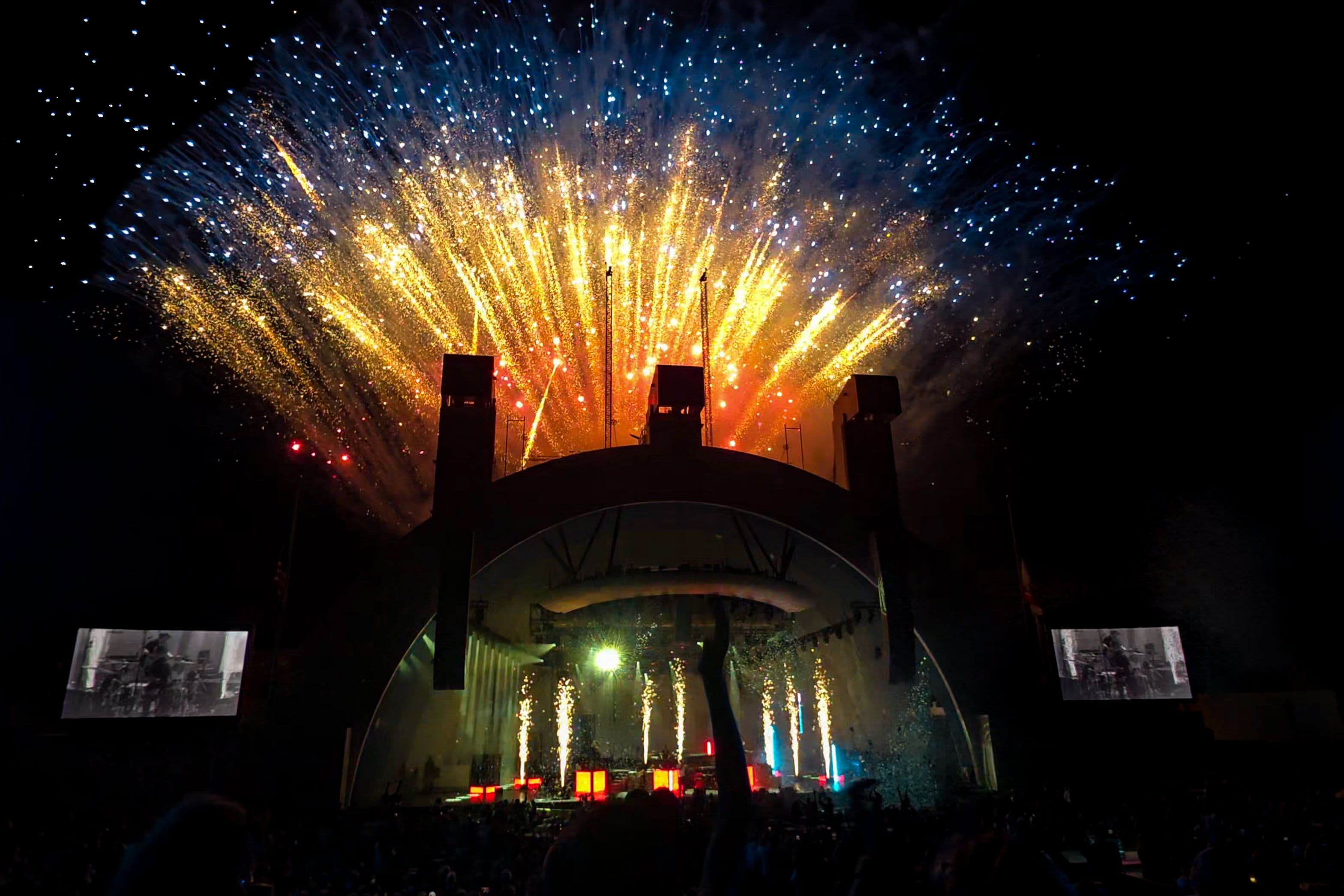 Gold, blue and white fireworks burst above the Hollywood Bowl shell while OneRepublic performs on the brightly lit stage below.