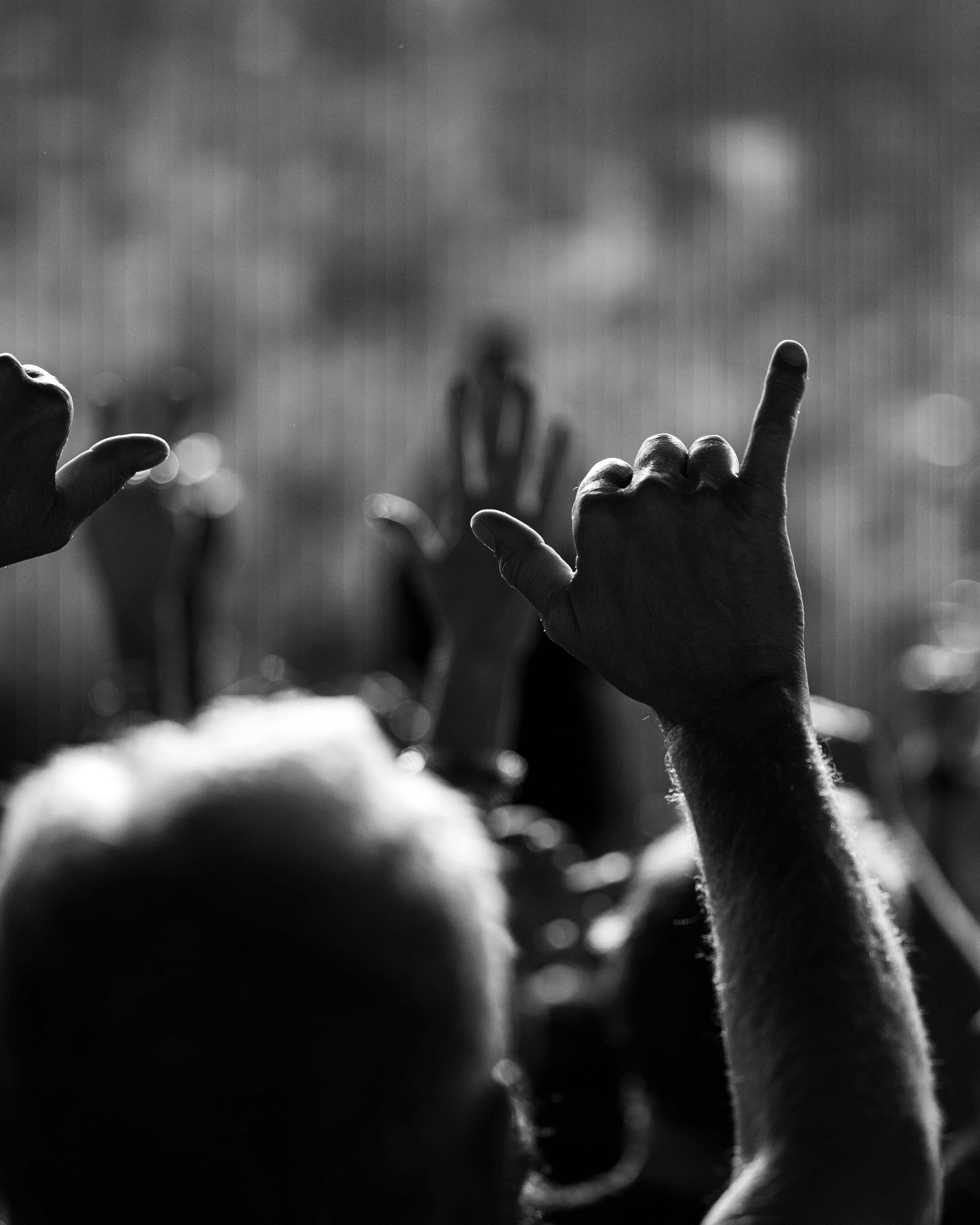 A concertgoer raises a hand toward the stage in a black-and-white crowd photograph during Train’s Greek Theatre performance.