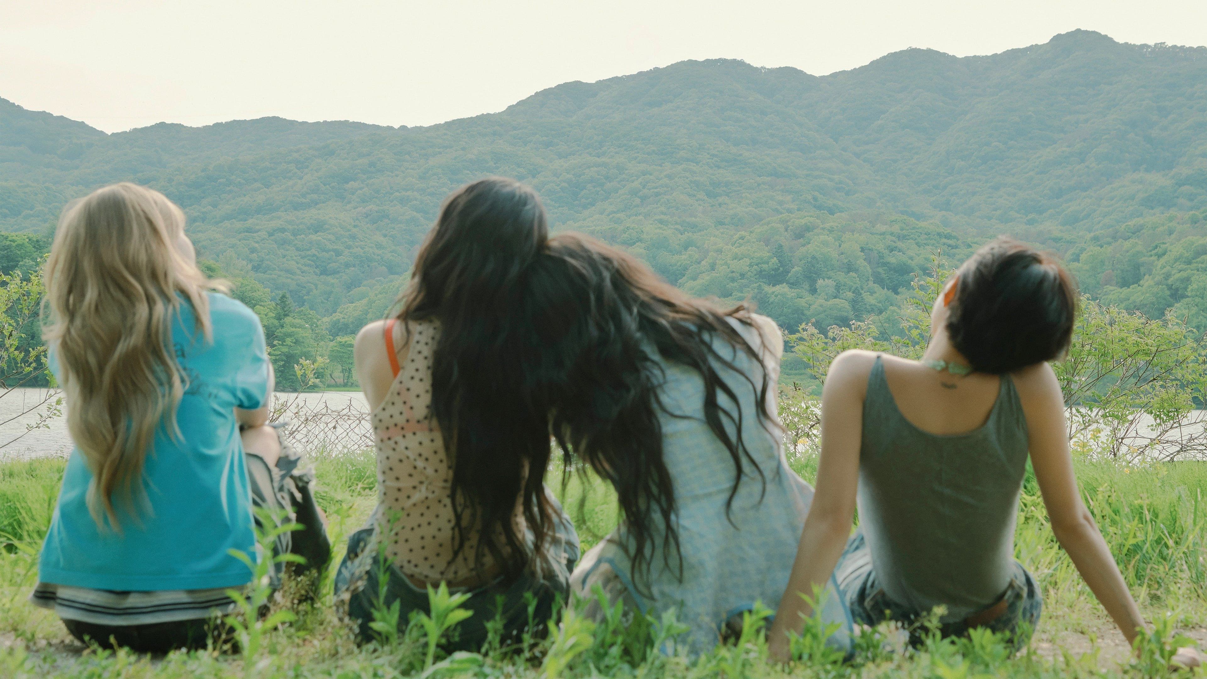 MAMAMOO members Solar, Moon Byul, Whee In and Hwa Sa sit together overlooking a lake and forested mountains.