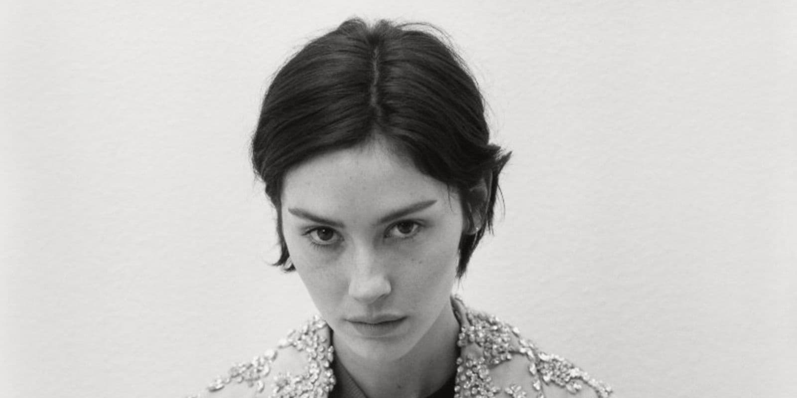 Gracie Abrams looks into the camera in a black-and-white close portrait.